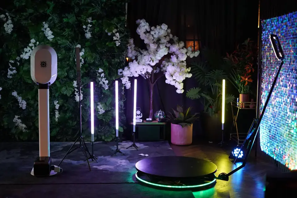 360° LED platform, white booth, and floral green wall in one event setup
