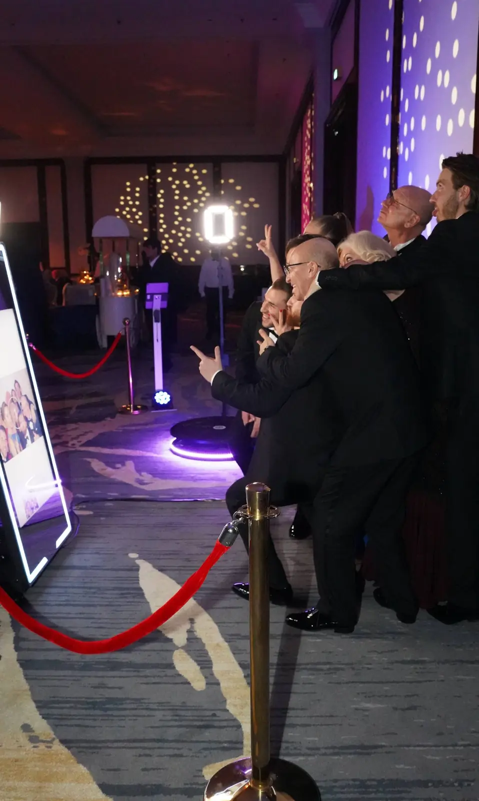 Guests crowding a mirror booth with a 360° platform glowing behind them