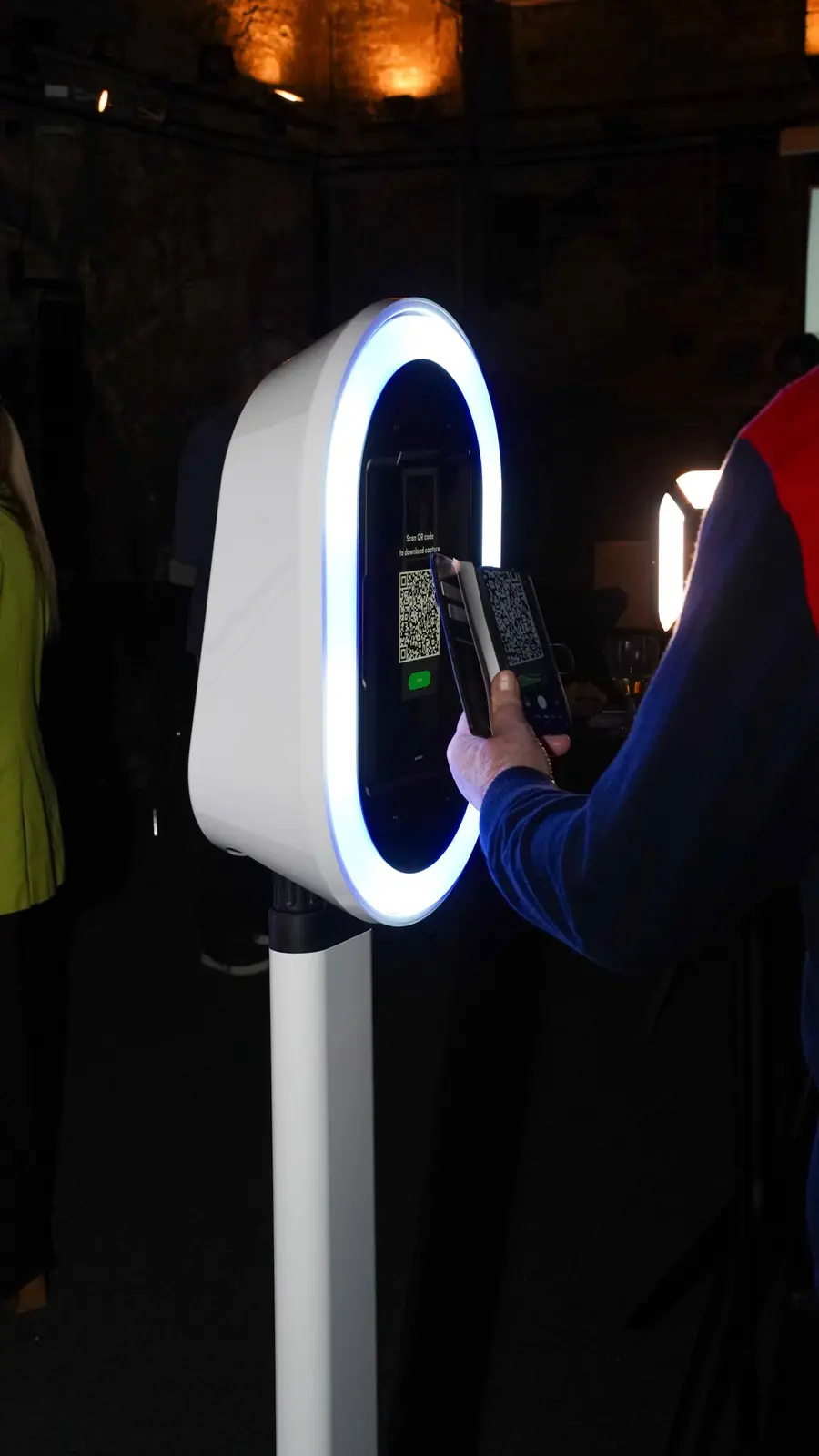 A guest scanning a QR code on a white ring-light booth to download their photo